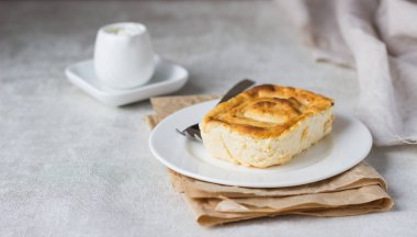 Süzme peynir güveç beyaz tabakta. Puding süzme peynir pişmiş.