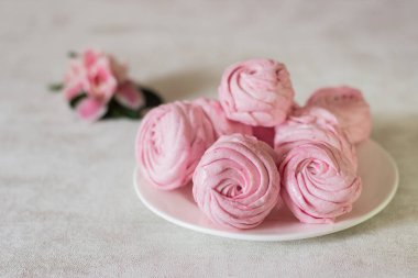 Güzel lezzetli tatlı. Bir beyaz plaka ve pembe çiçek pembe zephyr. Berry zephyr ışık gri arka plan üzerinde. 