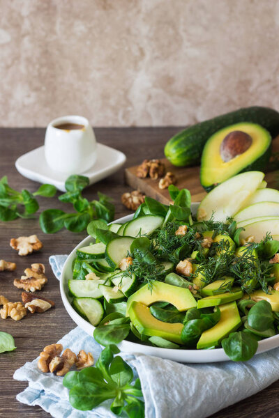 Green avocado cucumber salad with corn salad, apple, walnuts and dill. Detox food lunch. Diet concept.