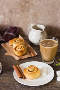 Ev yapımı tarçınlı çörek alır veya Cinnabon rustik masa kahve ile devam eder. Kahvaltıda tatlı geleneksel tatlı. Kopya alanı.