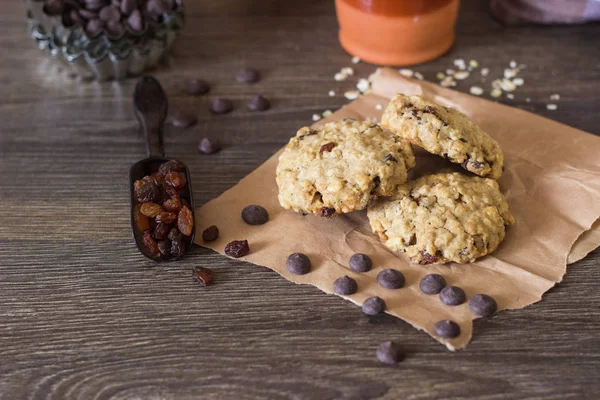 新鲜燕麦巧克力饼干与葡萄干和牛奶的成分烘焙饼干的木质背景 — 图库照片