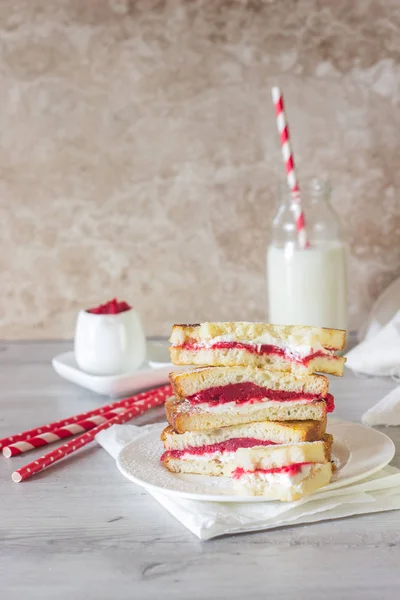 French toast with cream cheese and jam on a white plate and light background.  Tasty sandwich with cream cheese and jam.