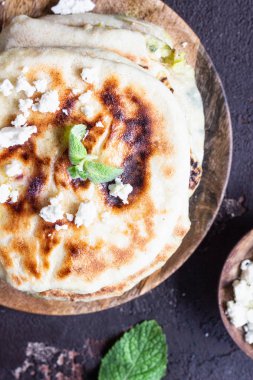 Tahta tabakta servis edilen soğan, nane ve peynir küçük düz ekmekler. Gozme - gevrek, altın rengi Türk ekmeği.