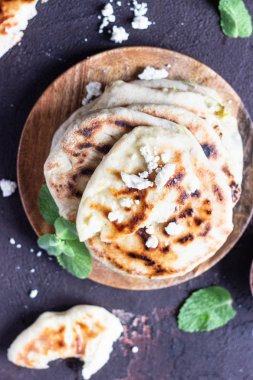 Tahta tabakta servis edilen soğan, nane ve peynir küçük düz ekmekler. Gozme - gevrek, altın rengi Türk ekmeği.