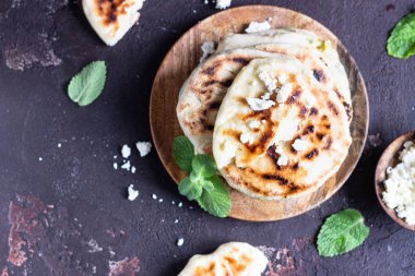 Tahta tabakta servis edilen soğan, nane ve peynir küçük düz ekmekler. Gozme - gevrek, altın rengi Türk ekmeği.