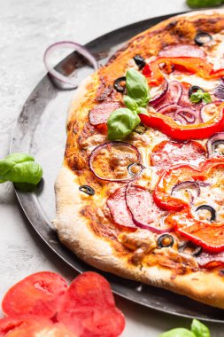 Salamlı, soğanlı, biberli, zeytinli, mozzarella peynirli ve siyah tepside fesleğenli lezzetli pizza. Ev yapımı sıcak biberli pizza..