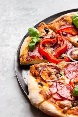 Salamlı, soğanlı, biberli, zeytinli, mozzarella peynirli ve siyah tepside fesleğenli lezzetli pizza. Ev yapımı sıcak biberli pizza..