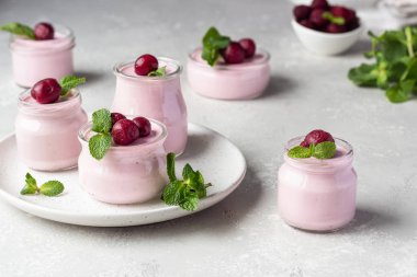 Taze kirazlı ve naneli İtalyan kirazlı panna cotta. Açık gri taş arka plan, seçici odak. Boşluğu kopyala.