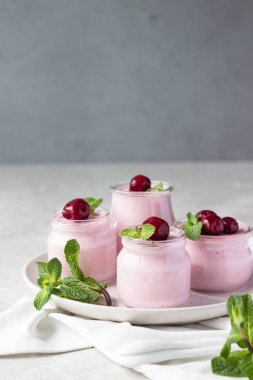 Taze kirazlı ve naneli İtalyan kirazlı panna cotta. Açık gri taş arka plan, seçici odak. Boşluğu kopyala.