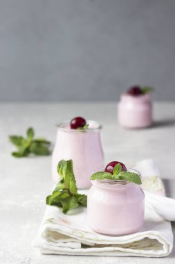 Taze kirazlı ve naneli İtalyan kirazlı panna cotta. Açık gri taş arka plan, seçici odak. Boşluğu kopyala.