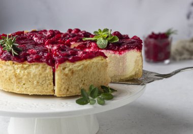 Kızılcık soslu klasik New York peynirli keki, nane ve biberiye, açık gri taş arka plan. 