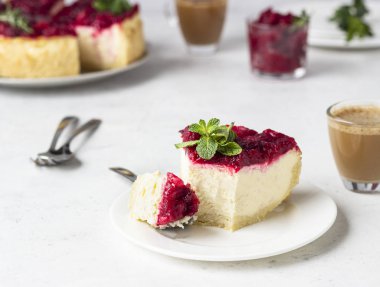 Kızılcık soslu klasik New York peynirli keki, nane ve biberiye, açık gri taş arka plan. 