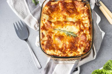 Geleneksel İtalyan lazanyası kıyma, domates ve peynirli. Açık gri beton arkaplan, seçici odak.