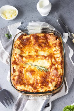 Geleneksel İtalyan lazanyası kıyma, domates ve peynirli. Açık gri beton arkaplan, seçici odak.