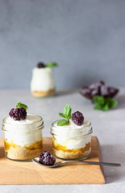 Ev yapımı tatlı yok (cheesecake, trifle, mousse) portakal ya da şeftali reçeli ile donmuş böğürtlen ve nane ile servis edilir. Açık gri taş arkaplan, boşluğu kopyala.