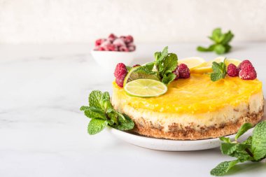 Limon dilimleri, limon dilimleri, donmuş ahududu ve seramik tabakta naneli limonlu vanilyalı cheesecake. Açık gri arkaplan.