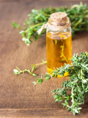 Taze kekik ve eski ahşap zeminli bir şişe kekik yağı..