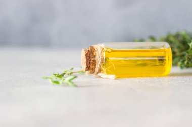 Bir şişe kekik (timüs) taze kekik ve açık gri taş zemin içeren temel yağ.