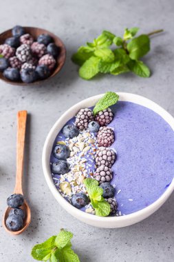 Üzümlü, böğürtlenli, hindistan cevizli ve tohumlu mor sihirli smoothie kasesi. Sağlıklı kahvaltı meyve suyu kasesi.