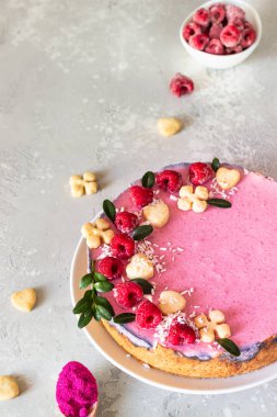 Taze ahududu, mini kurabiye ve açık gri arka planda hindistan cevizi taneleriyle süslenmiş ahududu kremalı kremalı kek (fırında cheesecake yok)..