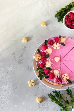 Taze ahududu, mini kurabiye ve açık gri arka planda hindistan cevizi taneleriyle süslenmiş ahududu kremalı kremalı kek (fırında cheesecake yok)..