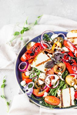 Izgara haloumi (halloumi) peynirli salata cadı domatesi, fırında biber, mikro yeşil ve mavi tabakta soğan. Keto diyeti, sağlıklı yiyecekler.