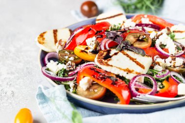 Izgara haloumi (halloumi) peynirli salata cadı domatesi, fırında biber, mikro yeşil ve mavi tabakta soğan. Keto diyeti, sağlıklı yiyecekler.