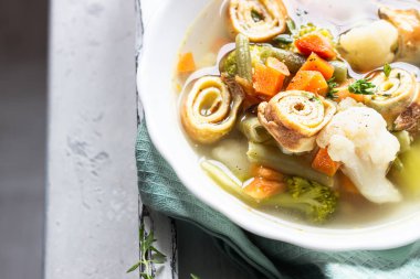 Açık gri arka planda yumurta krepli sebze çorbası. Geleneksel Alman Flaedlesuppe ve Avusturya Frittatensuppe. 