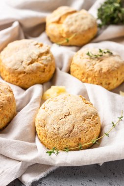 Peynirli çörekler, bir parça peynir ve gri peçeteye kekik. Gri taş arkaplan, tonlu görüntü.