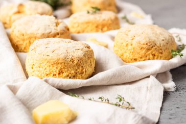 Peynirli çörekler, bir parça peynir ve gri peçeteye kekik. Gri taş arkaplan, tonlu görüntü.