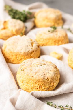 Peynirli çörekler, bir parça peynir ve gri peçeteye kekik. Gri taş arkaplan, tonlu görüntü.