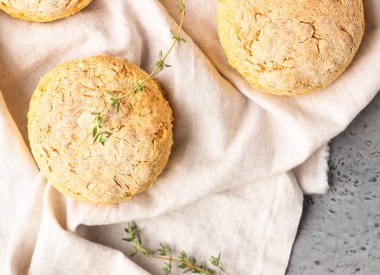 Peynirli çörekler, bir parça peynir ve gri peçeteye kekik. Gri taş arkaplan, tonlu görüntü.