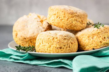 Ev yapımı peynirli çörekler, çörekler ve gri seramik tabakta kekik.. 