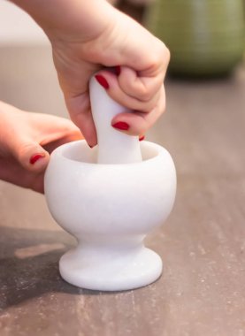 Pounder (mermer havan topu) ve elinde tokmağı olan kadın mutfakta bir şeyler hazırlıyor.. 