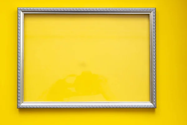Silver frame for painting or picture on a bright yellow paper background. Frame template for place image or text inside.