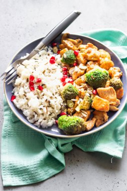 Pirinçli köri tavuğu, mantar ve nar tohumlarıyla süslenmiş brokoli. Sağlıklı yiyecekler. Asya mutfağı.