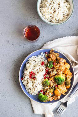 Pirinçli köri tavuğu, mantar ve nar tohumlarıyla süslenmiş brokoli. Sağlıklı yiyecekler. Asya mutfağı.