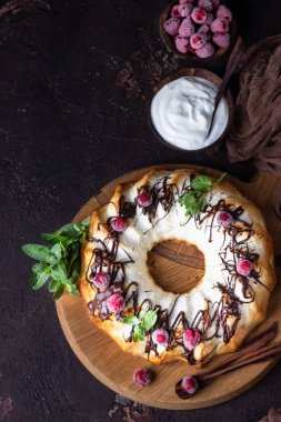 Süzme peynir fırınlanmış puding ya da çikolata jöleli güveç ahududu ve nane ile süslenmiş. Karanlık ruh hali fotoğrafı, kahverengi taş arka plan..