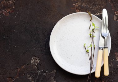 Koyu kahverengi taş masada çatal ve bıçakla dolu boş bir tabak. Masa düzenlemesi. Model.