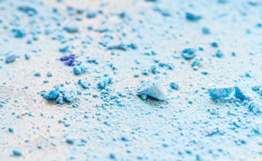 Parçalanmış (ezilmiş) küçük mavi kremalar, açık gri taş zemin.