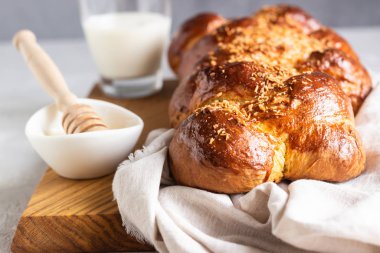Açık gri taş zemin üzerinde ahşap bir kesim tahtasının üzerinde ev yapımı challah ekmeği. Şabat, hebraizm geleneksel ekmek.