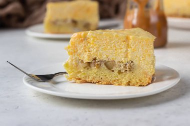 Bir dilim balkabaklı cheesecake ve karamel soslu açık gri taş zemin. Seçici odak. 