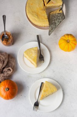 Bir dilim balkabaklı cheesecake ve karamel soslu açık gri taş zemin. Seçici odak. 