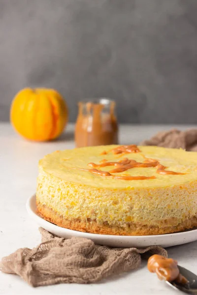 Pumpkin cheesecake with caramel sauce, light grey stone background. Selective focus.
