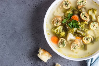 Sebzeli çorba ve beyaz tabakta yumurtalı krep, açık gri arka plan. Geleneksel Alman Flaedlesuppe ve Avusturya Frittatensuppe. 