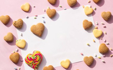 Kalp şeklinde kurabiyeler ve renkli serpiştirilmiş kağıtlar, metin için kopyalama alanı. Pembe kağıt arka plan. Aşk konsepti, 8 Mart, Uluslararası Mutlu Kadınlar Günü, Doğum günü.