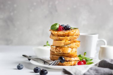 Yaban mersinli bir yığın Fransız tostu, kurutulmuş kiraz, nane ve kahve, açık gri arka plan. Kahvaltı ya da atıştırmalık konsepti.