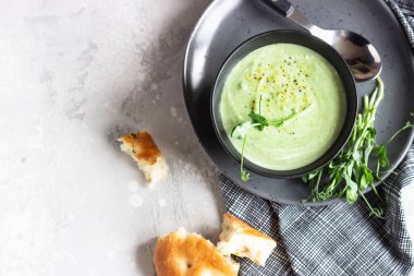 Avokado ile vegan kremalı çorba ve mikro yeşillik ve ekmekle servis edilen ıspanak. Diyet gıda konsepti. Vejetaryen ve vejetaryen yemekleri. Üst görünüm. 