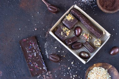 Koyu kahverengi arka planda bir kutuda çeşitli çikolata şekerleri var.. 