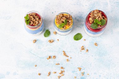 Reçelli vejetaryen mavi spirulina chia pudingi ve açık mavi bir masada cam kavanozlarda granola. Sağlıklı beslenme, diyet ve zindelik menüsü kavramı. Kahvaltı için çeşitli katmanlı tatlılar.. 